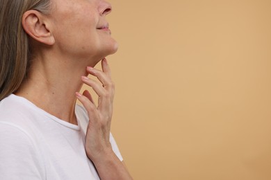 Mature woman with healthy skin on beige background, closeup. Space for text