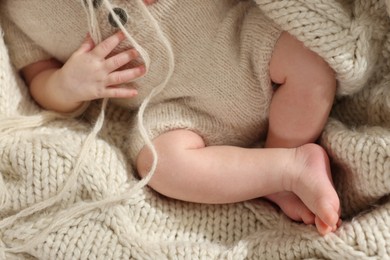 Photo of Top view of adorable newborn baby on knitted plaid, closeup