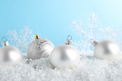 Photo of Christmas tree decoration on artificial snow against light blue background
