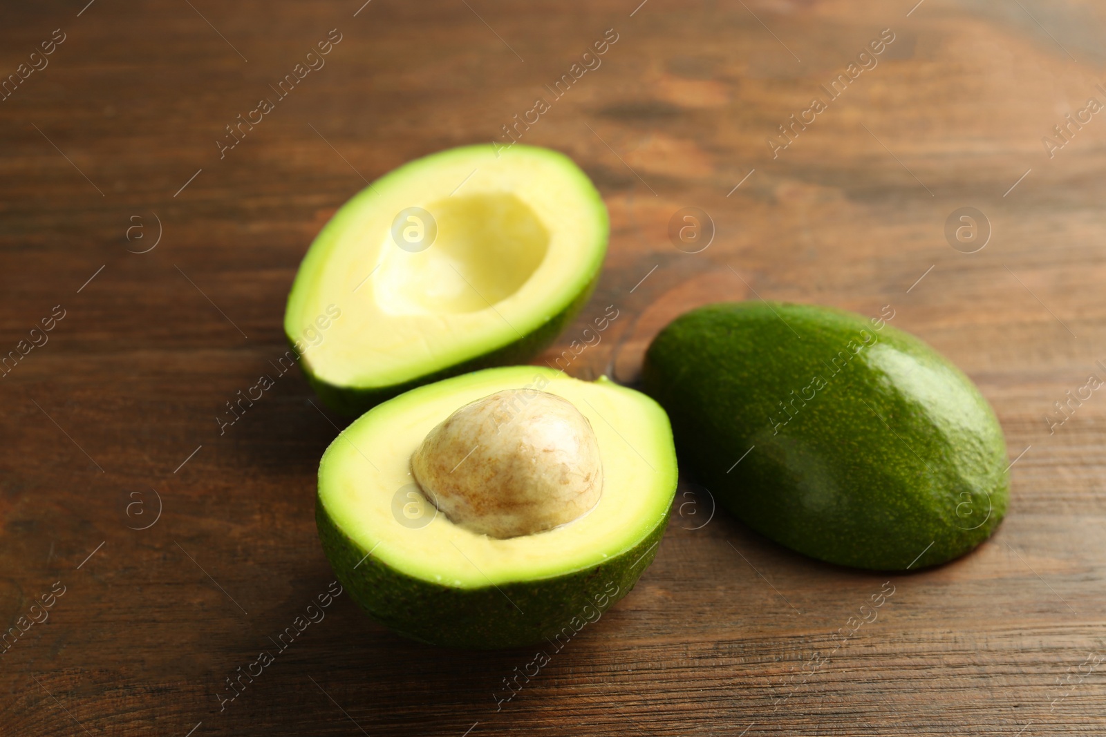 Photo of Tasty ripe green avocados on wooden background