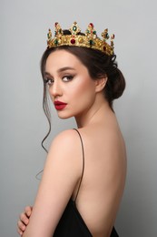 Photo of Beautiful young woman wearing luxurious crown on light grey background