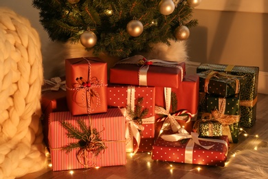 Pile of gift boxes near Christmas tree on floor