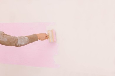 Photo of Decorator painting wall with brush indoors, closeup