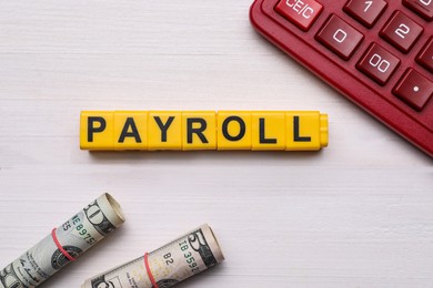 Word Payroll made of yellow cubes with letters, dollars and calculator on white wooden table, flat lay