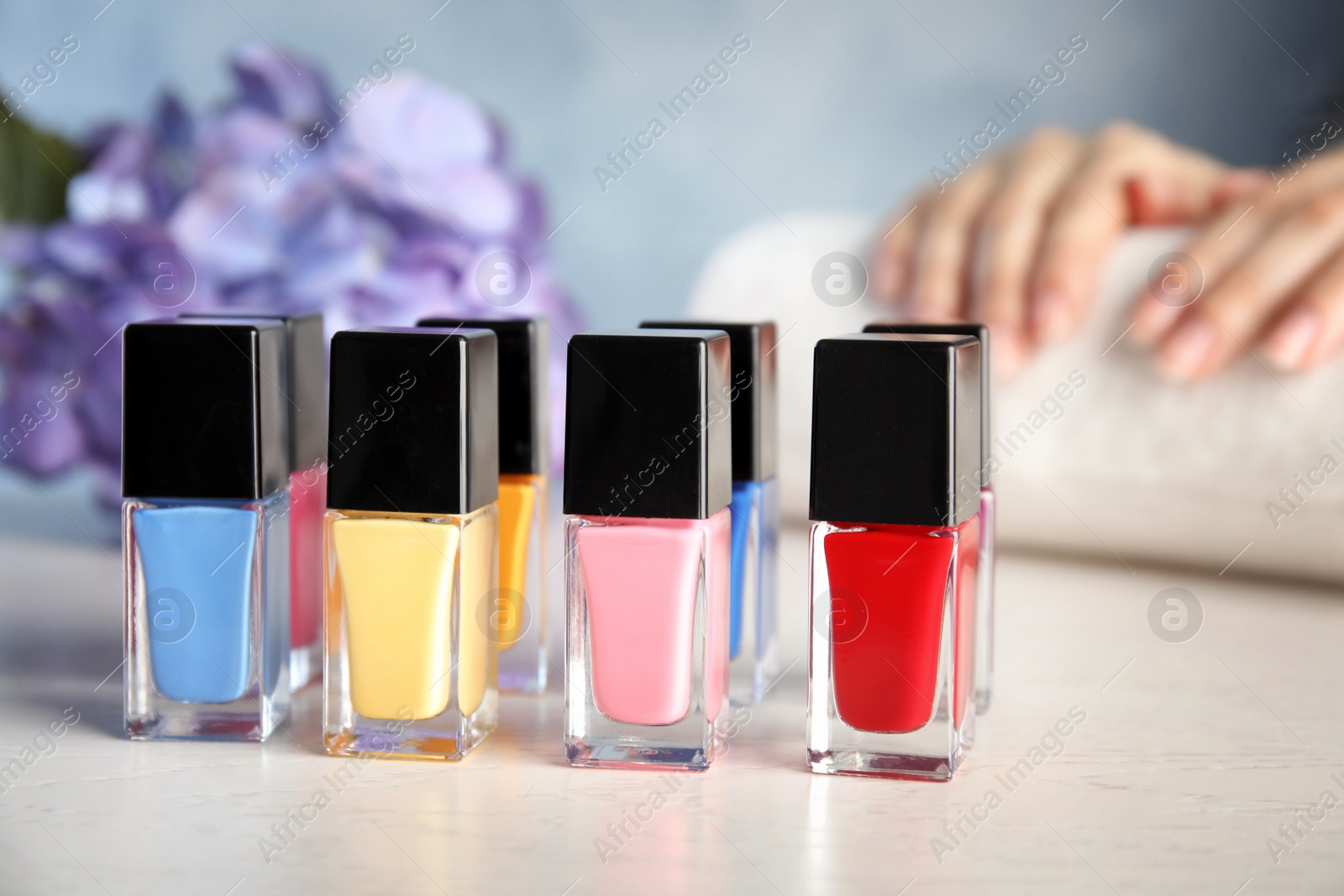 Photo of Bottles of bright nail polish and blurred woman on background