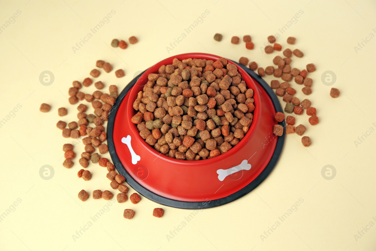 Photo of Dry dog food and feeding bowl on beige background