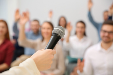 Photo of Business trainer with microphone answering questions indoors, closeup