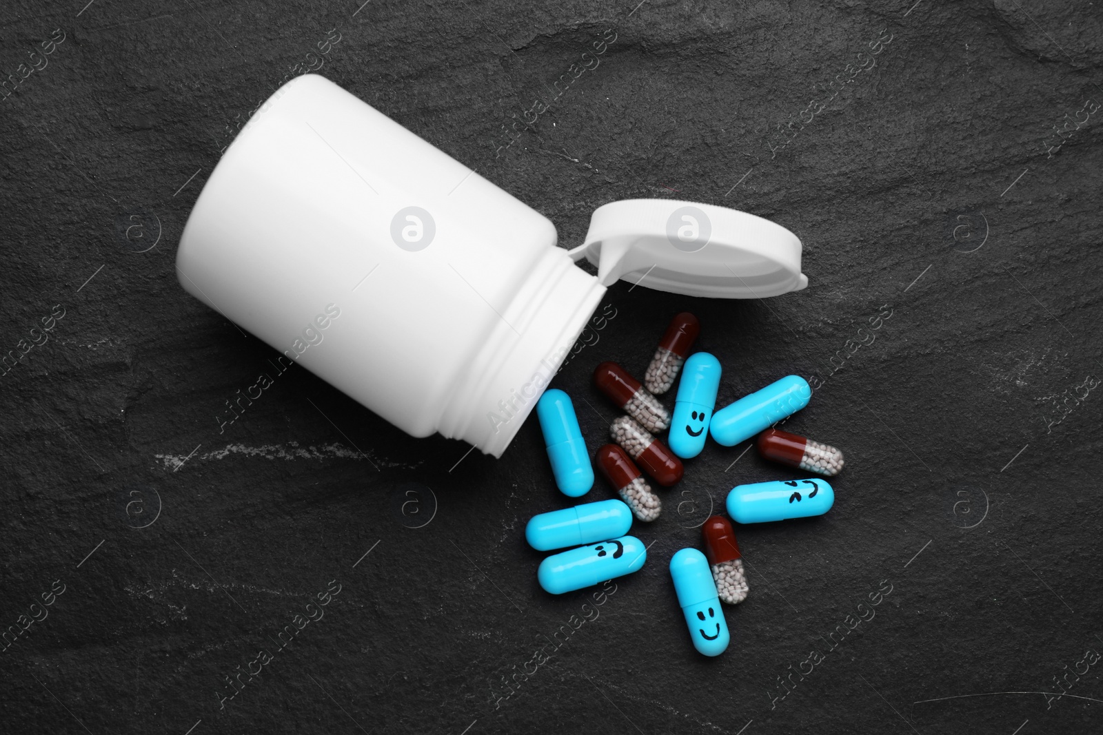 Photo of Antidepressants with happy emoticons and medical jar on black background, flat lay