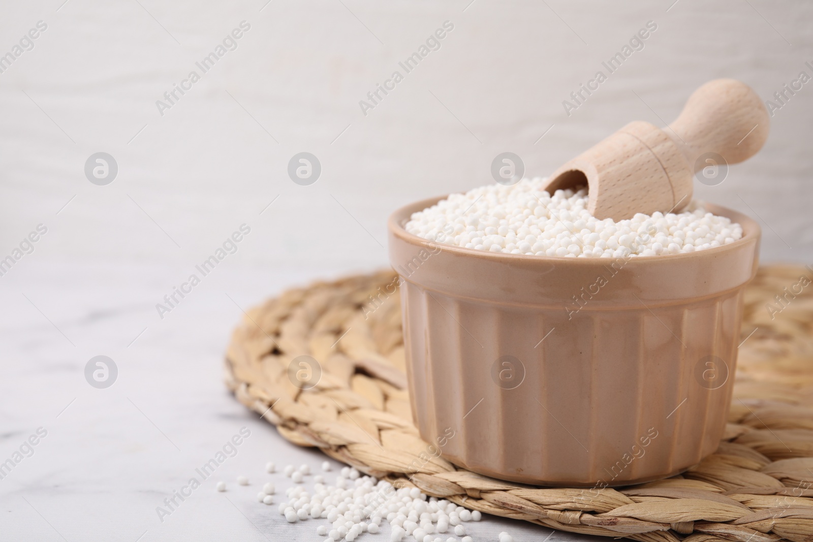 Photo of Tapioca pearls and scoop in bowl on table. Space for text