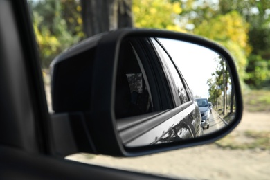 Photo of Closeup of car side rear view mirror on sunny day