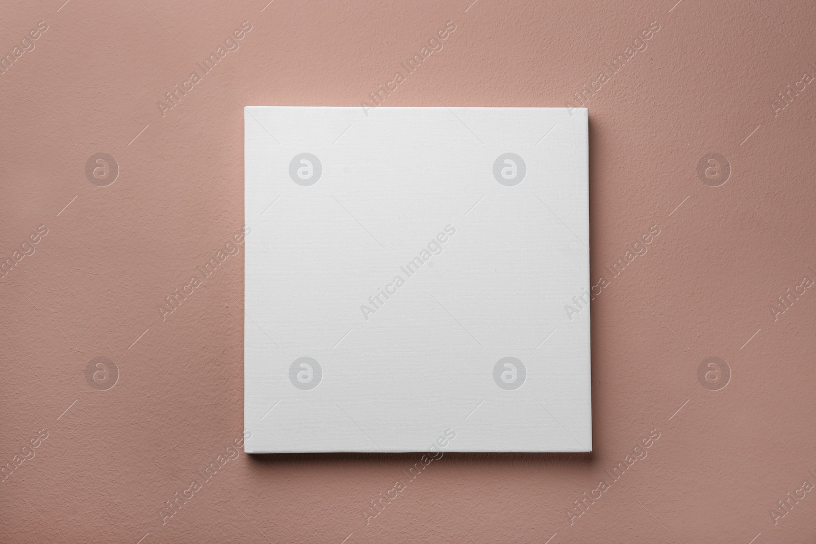 Photo of Blank canvas on pale pink wall. Space for design