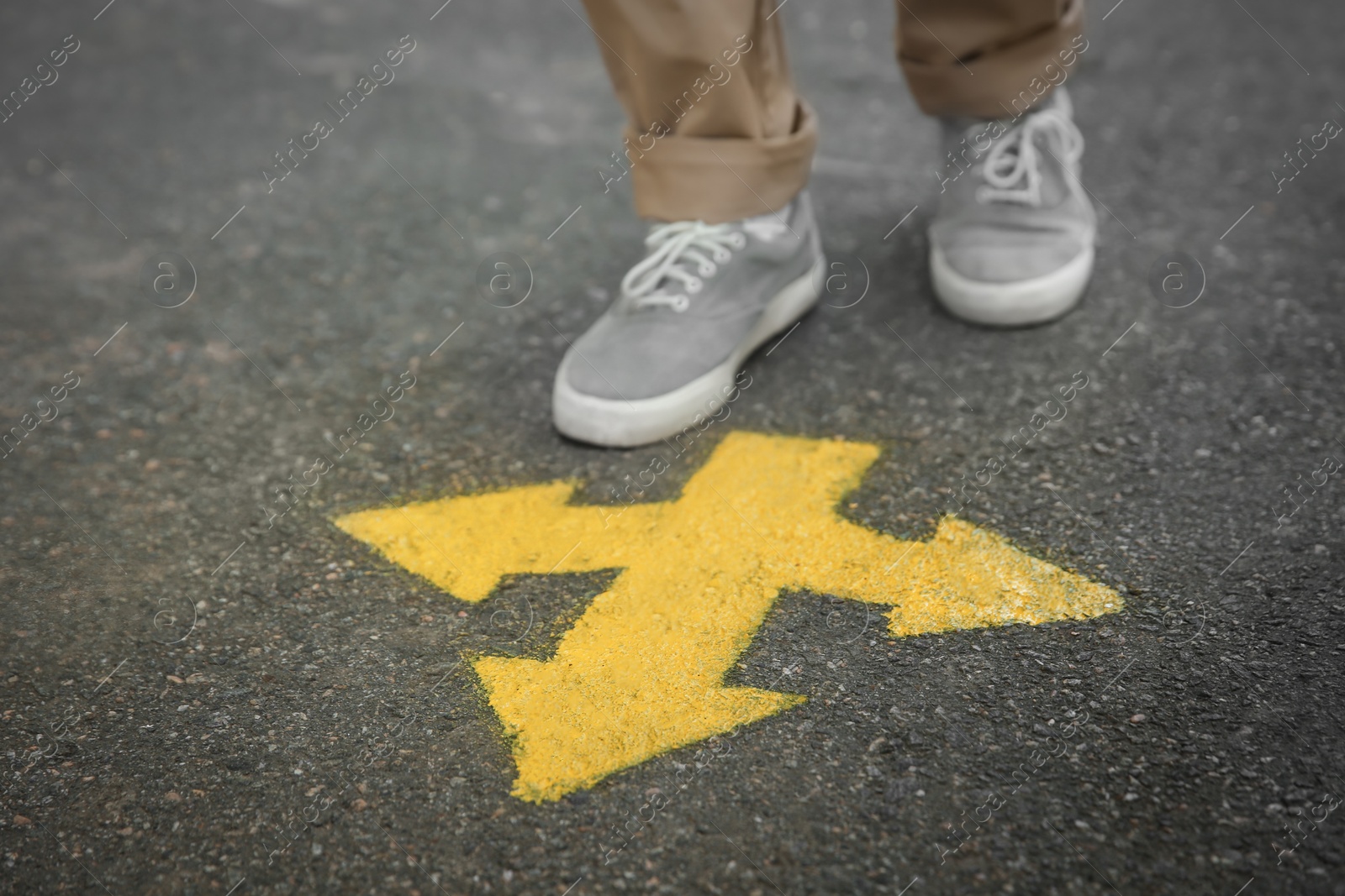 Photo of Man standing near arrow on asphalt, closeup