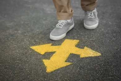 Photo of Man standing near arrow on asphalt, closeup