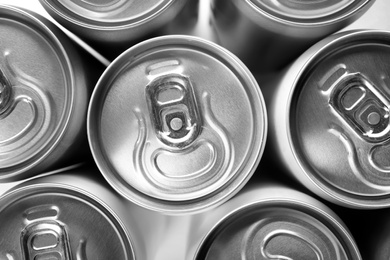 Photo of Aluminum cans with cold beverage as background, top view