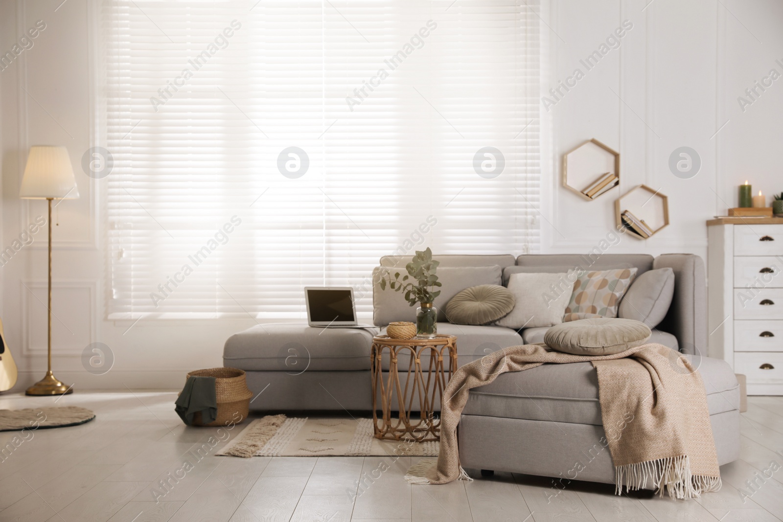 Photo of Living room with comfortable grey sofa, ottoman and stylish interior elements near window