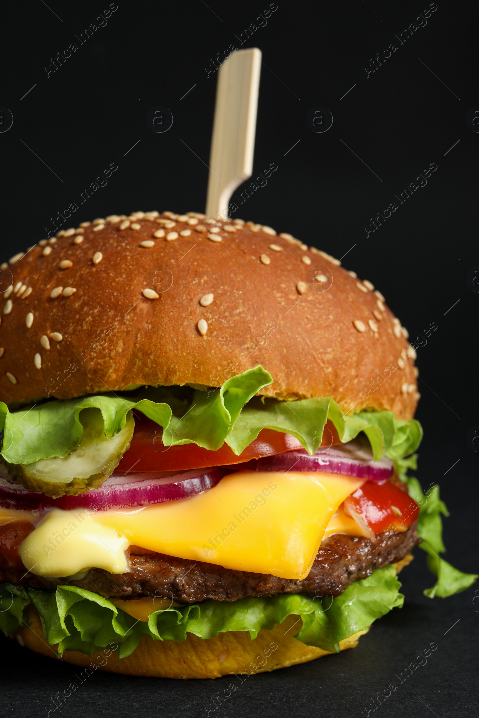 Photo of Delicious burger with beef patty and lettuce on black background, closeup
