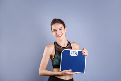 Photo of Young beautiful woman with scales on color background. Weight loss motivation
