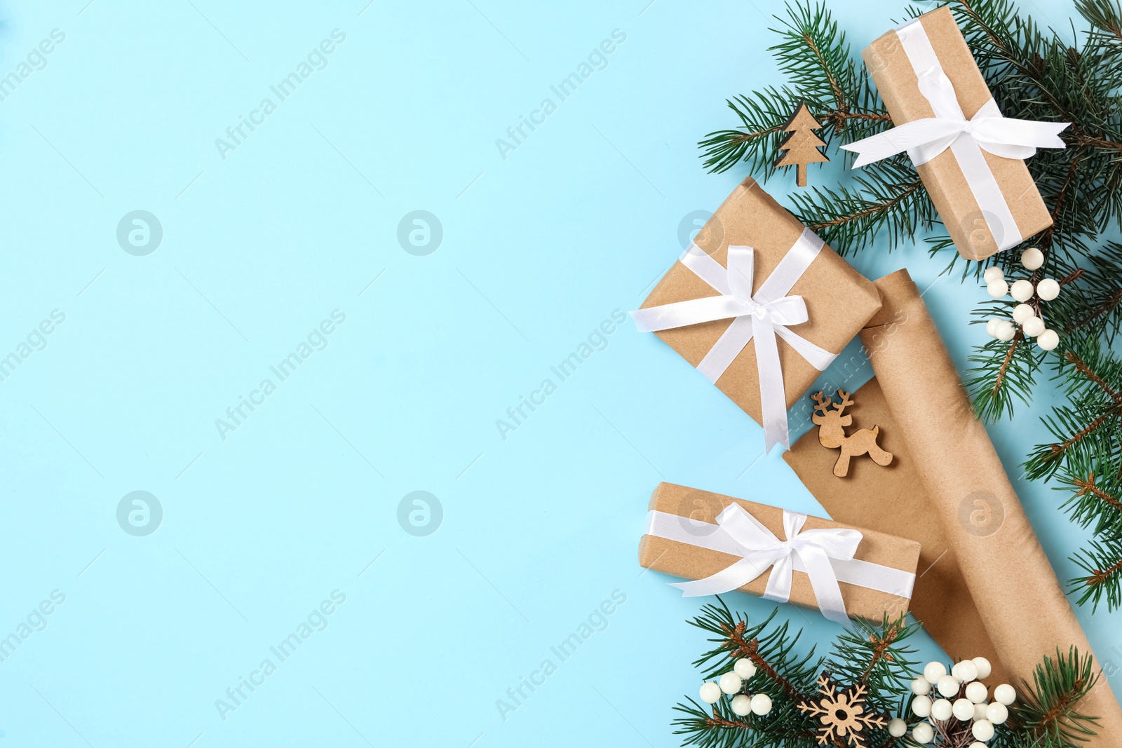 Photo of Christmas gift boxes and fir branches on light blue background, flat lay. Space for text