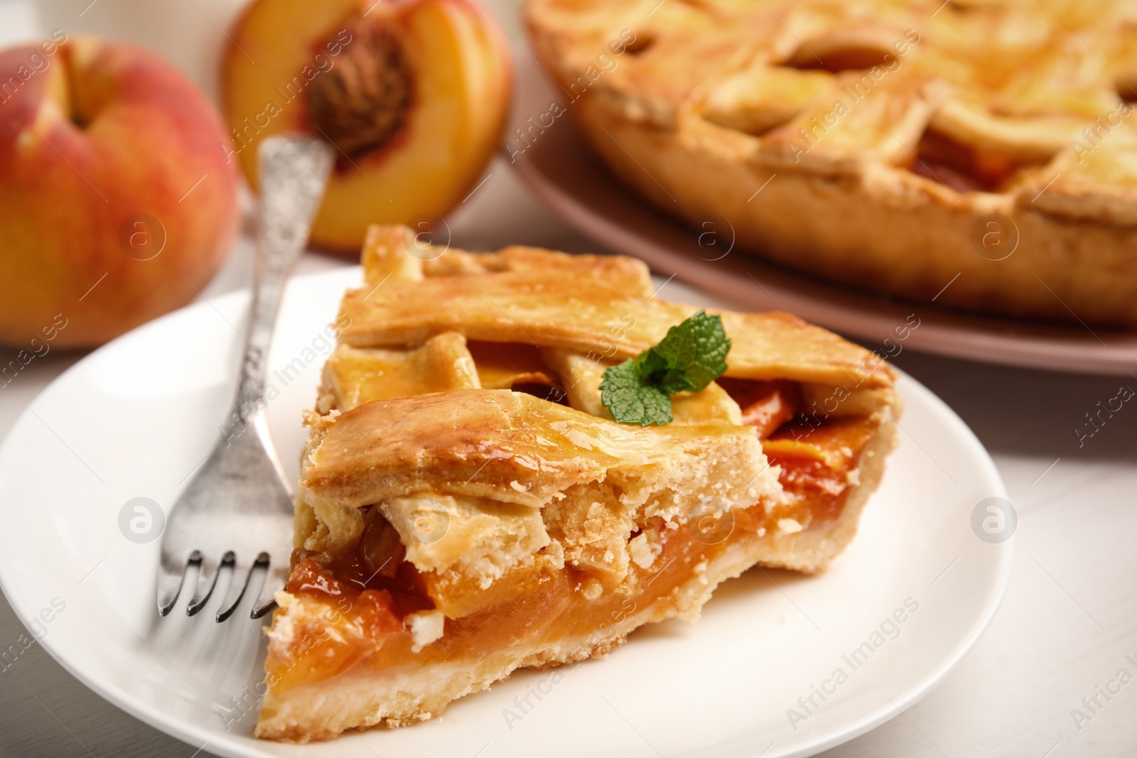 Photo of Piece of delicious fresh peach pie served on white table, closeup