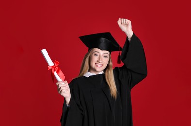 Happy student with diploma on red background