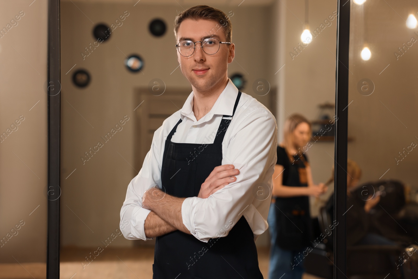 Photo of Portrait of professional hairdresser wearing apron in beauty salon