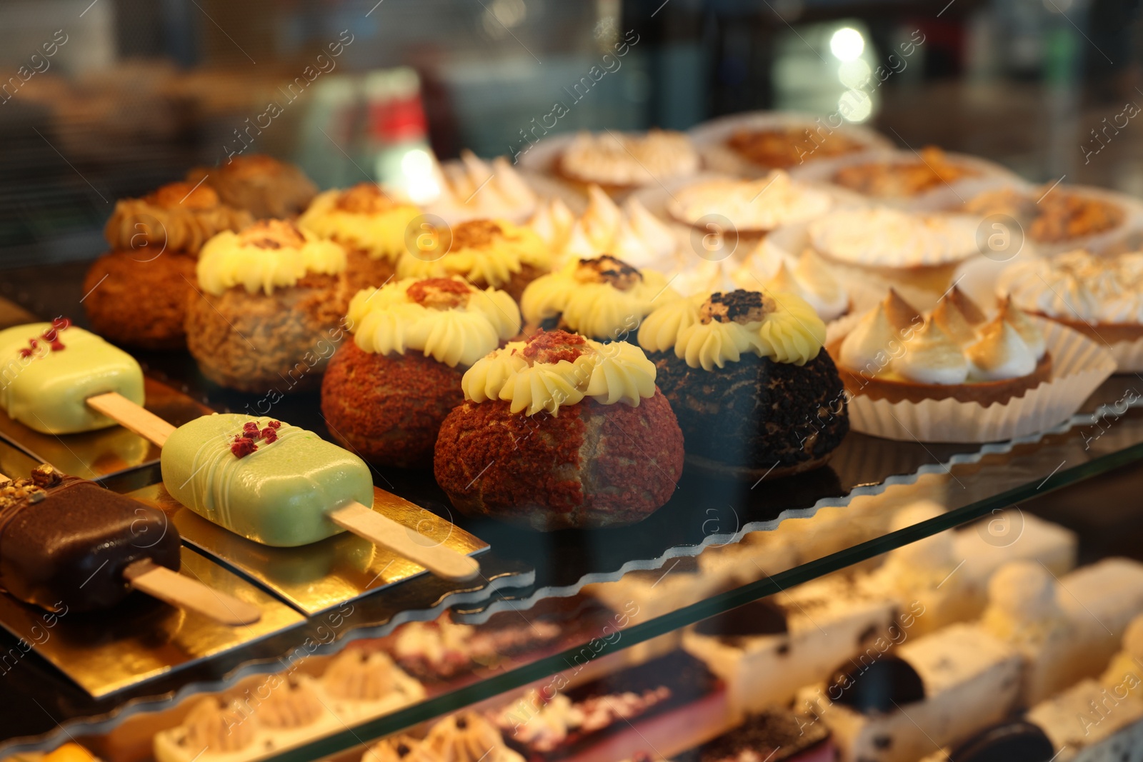 Photo of Different tasty desserts on counter in bakery shop, closeup