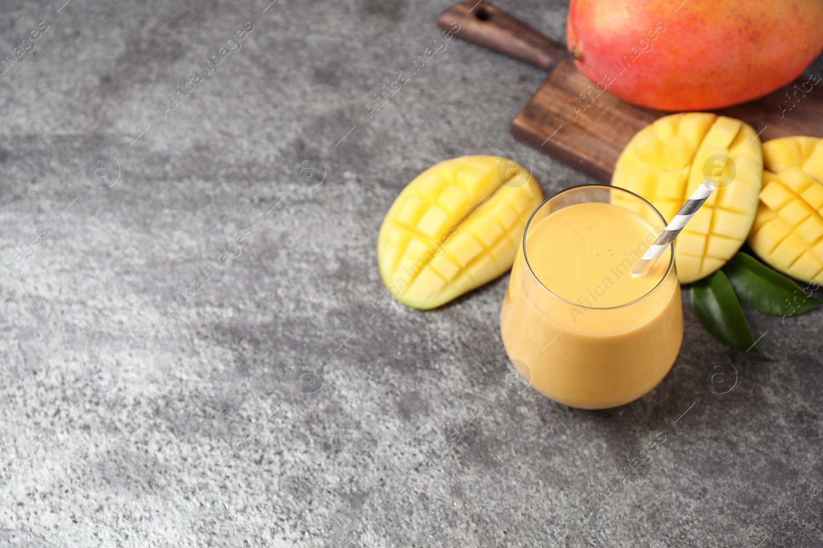 Photo of Fresh delicious mango drink on grey table. Space for text