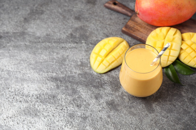 Photo of Fresh delicious mango drink on grey table. Space for text