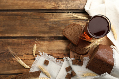 Photo of Flat lay composition with delicious kvass, spikes and bread on wooden table, space for text