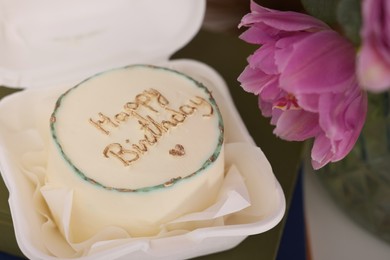 Photo of Delicious decorated Birthday cake and beautiful flowers on table indoors, closeup