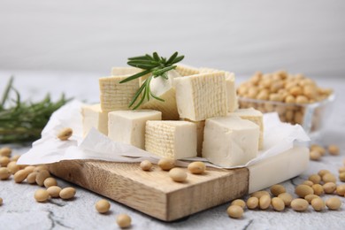 Photo of Delicious tofu cheese, rosemary and soybeans on light gray textured table, closeup