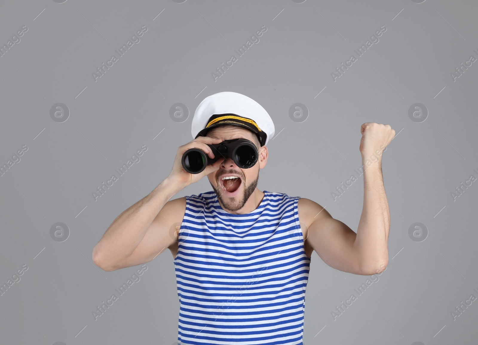 Photo of Happy sailor looking through binoculars on grey background