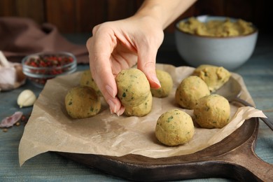 Photo of Woman making falafel balls at light blue wooden table, closeup