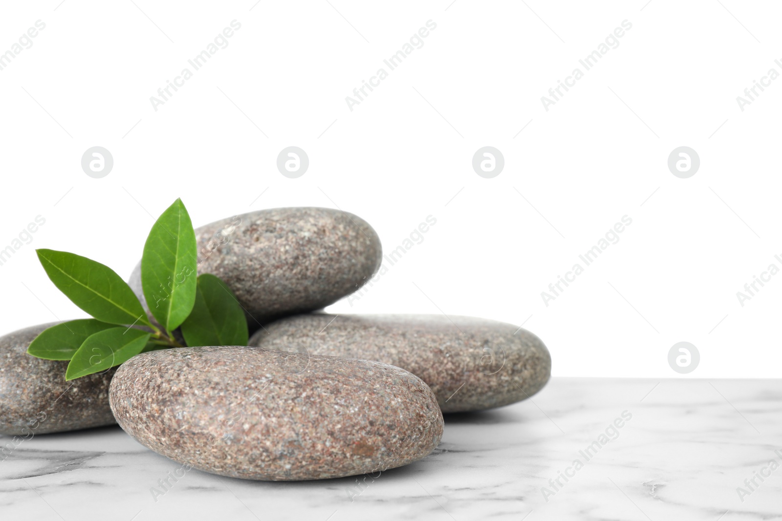 Photo of Spa stones with green branch on table against white background. Space for text