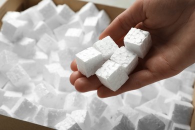 Photo of Woman holding styrofoam cubes over box, closeup