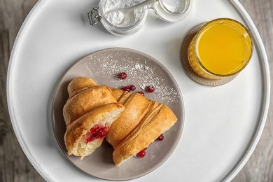 Photo of Tasty croissant with jam and glass of juice on table, top view