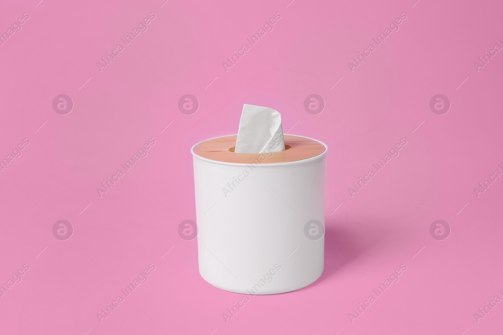 Photo of Holder with paper tissues on pink background