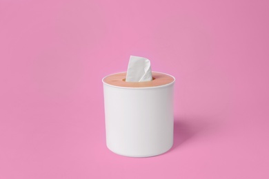 Photo of Holder with paper tissues on pink background