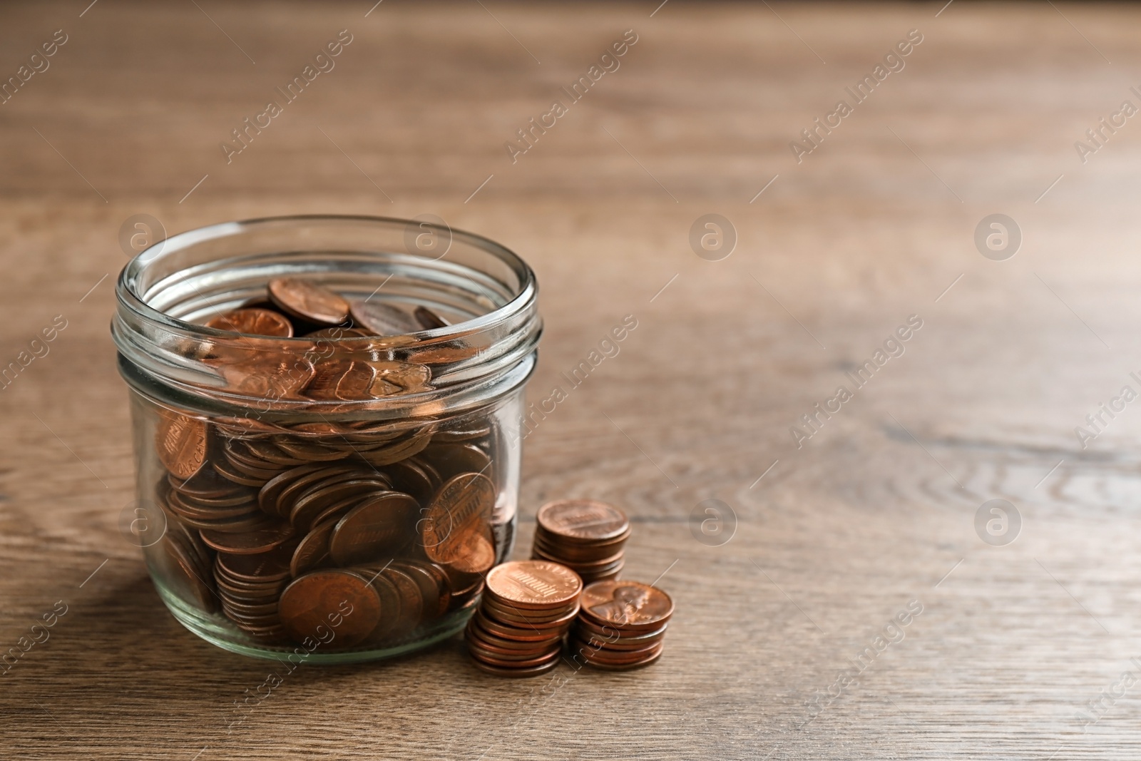 Photo of Glass jar with coins on wooden table, space for text. Money saving concept