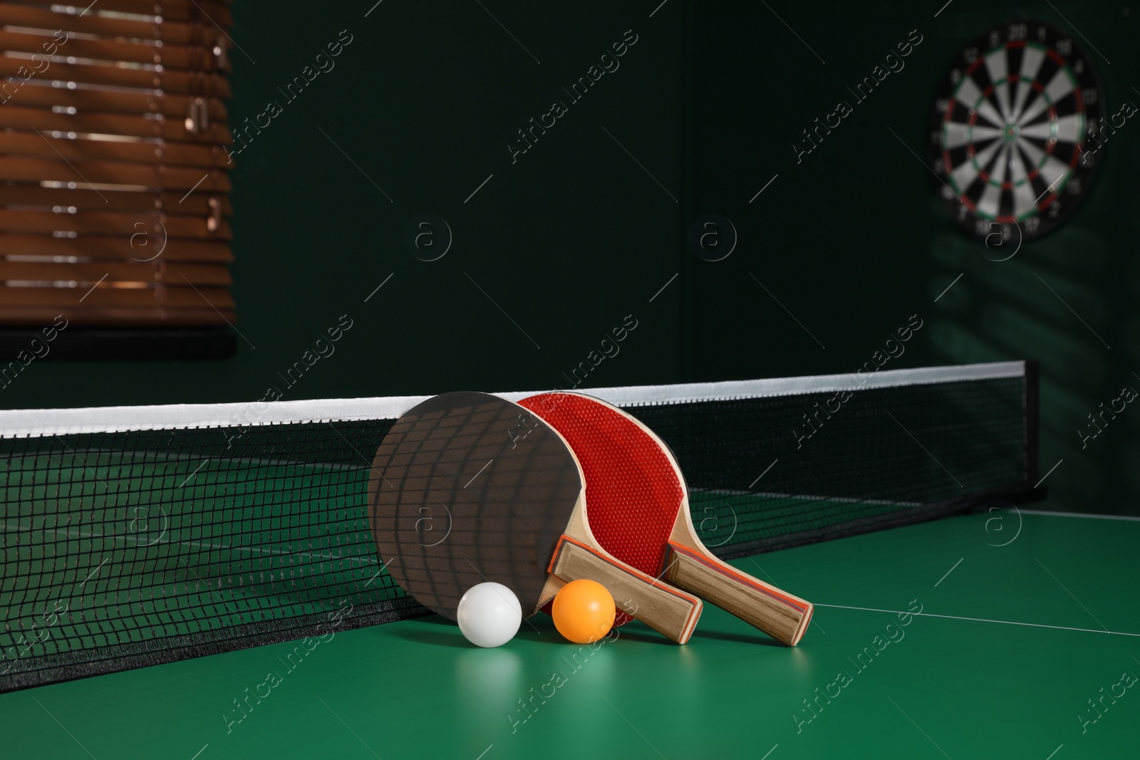 Photo of Rackets and balls on green ping pong table indoors. Space for text