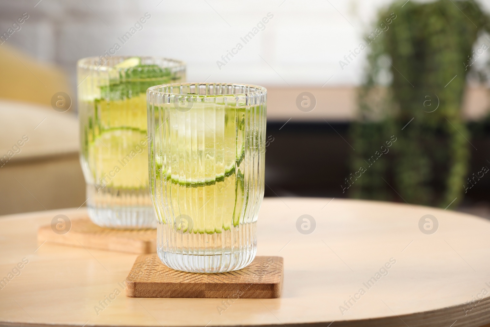 Photo of Glasses of lemonade and stylish cup coasters on wooden table in room. Space for text