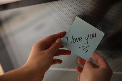 Photo of Woman with sticky note saying I Love You near oven door in kitchen, closeup. Romantic message