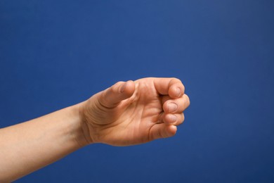 Woman holding something in hand on blue background, closeup. Space for text