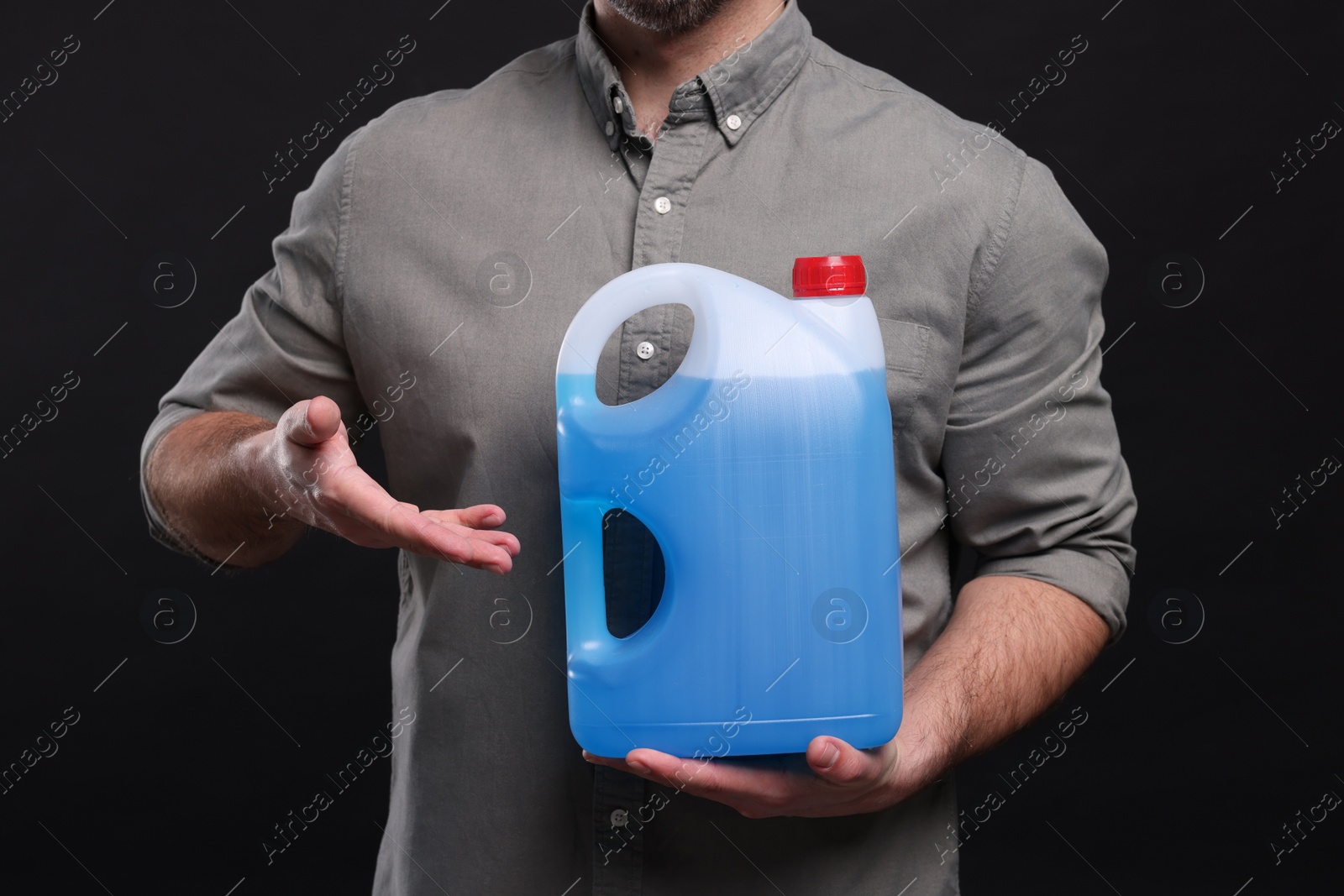 Photo of Man showing canister with blue liquid on black background, closeup