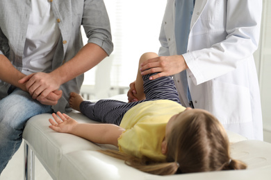 Professional orthopedist examining little patient's leg in clinic