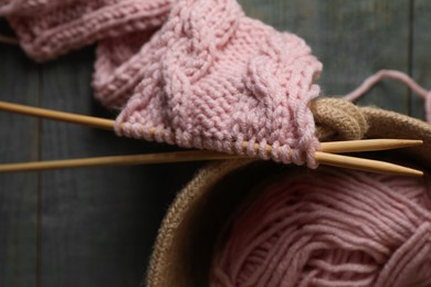 Photo of Soft pink woolen yarn, knitting and needles on wooden table, top view