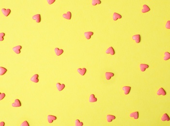 Photo of Bright heart shaped sprinkles on yellow background, flat lay