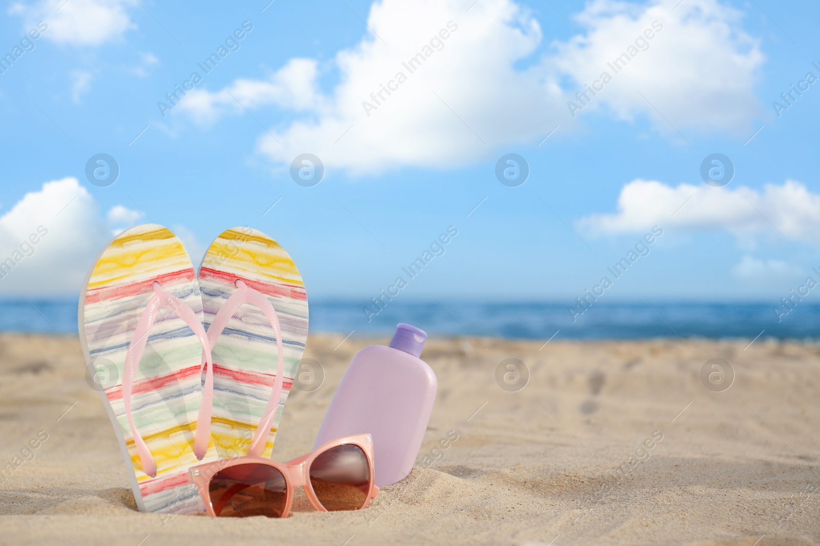 Photo of Different stylish beach objects on sand near sea. Space for text