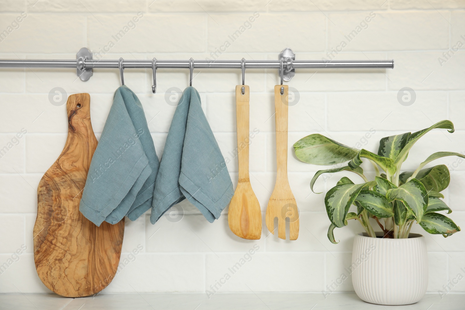 Photo of Clean towels and utensils hanging on rack in kitchen