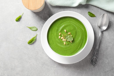 Flat lay composition with fresh green healthy spinach soup on grey table